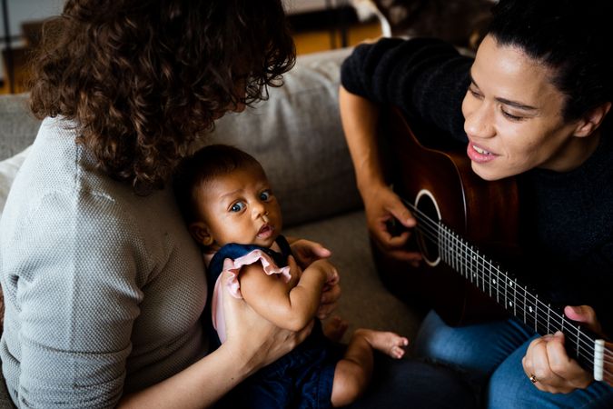 Female playing acoustic guitar for baby and partner
