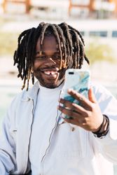 Cheerful Black man taking selfie on smartphone