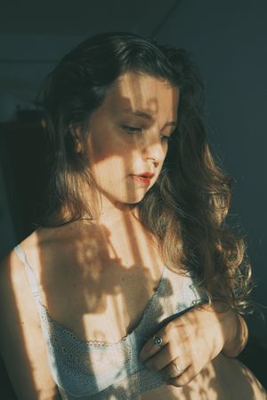 Portrait of woman in gray bra with floral shadow looking down