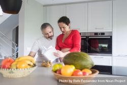 Smiling couple consulting recipe book in bright kitchen 4OgnL4