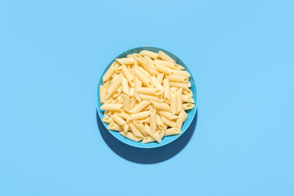 Penne pasta top view isolated on a blue background