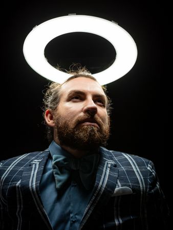 Smart bearded man under circle light on black background