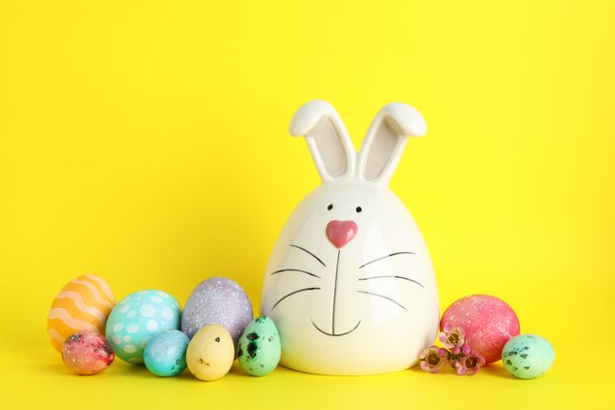 Decorated bunny and Easter eggs on color background. Space for text