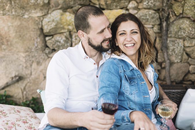 Smiling couple sitting on a terrace while bonding and enjoying a cup of wine
