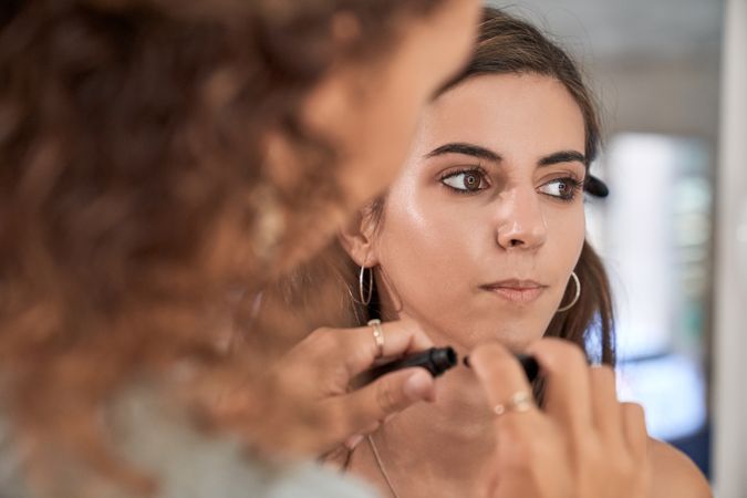 Unrecognizable woman applying cosmetic product on client