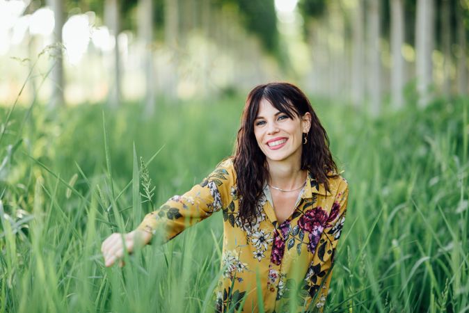 Content brunette female looking at camera playing in field of tall grass