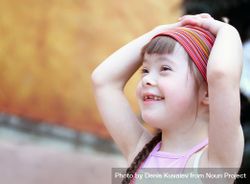 Portrait of a girl with Down syndrome in a pink headband 48JxR0