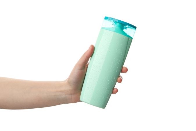 Female hand holds shampoo bottle, isolated on light background