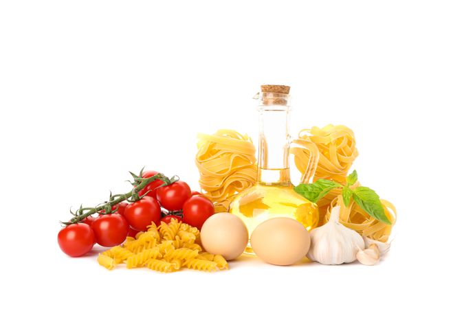 Pasta, olive oil, tomatoes, eggs and garlic isolated on light background. Uncooked whole wheat pasta