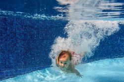 Cute little boy diving in underwater in pool