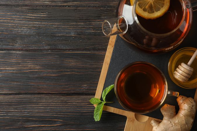 Cup of tea, mint, honey, ginger and teapot on wooden background, top view