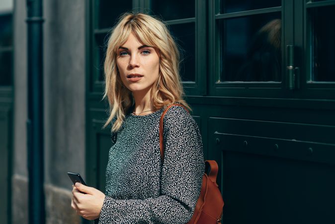 Blonde female wearing casual clothes outdoors with cell phone, copy space