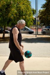 Middle aged man playing basketball on a street court 489r7b
