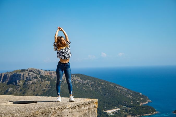 Woman enjoying weather on concrete block near sea
