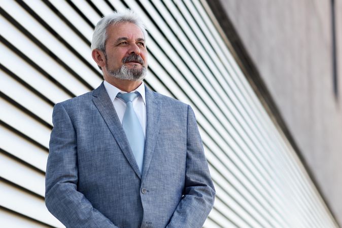 Portrait of a businessman standing next to lined wall