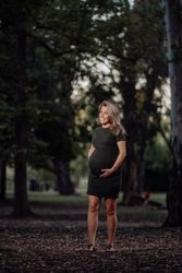 Charming pregnant woman standing on walkway in park