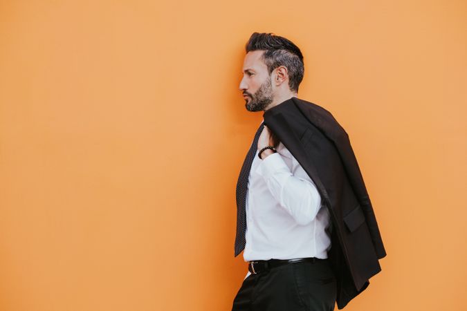 Adult smiling stylish man in costume near orange wall on street
