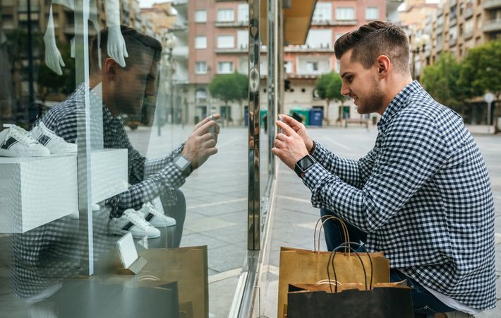 Man taking a photo of a shop window of a fashion store