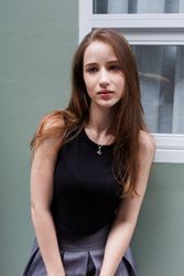 Portrait of young woman standing outside of window