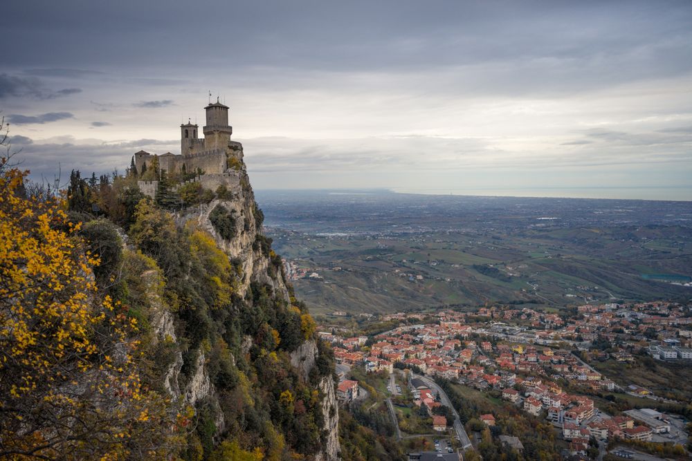 Stone peak with castle overgrown with trees and bushes rush into sky