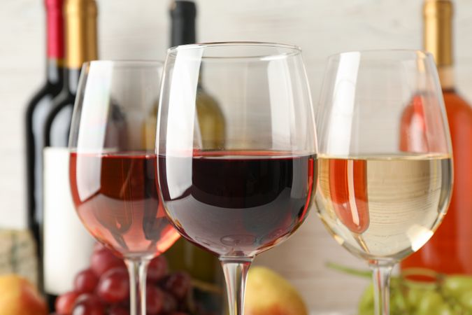 Grape, bottles and glasses with wine on blank background, close up