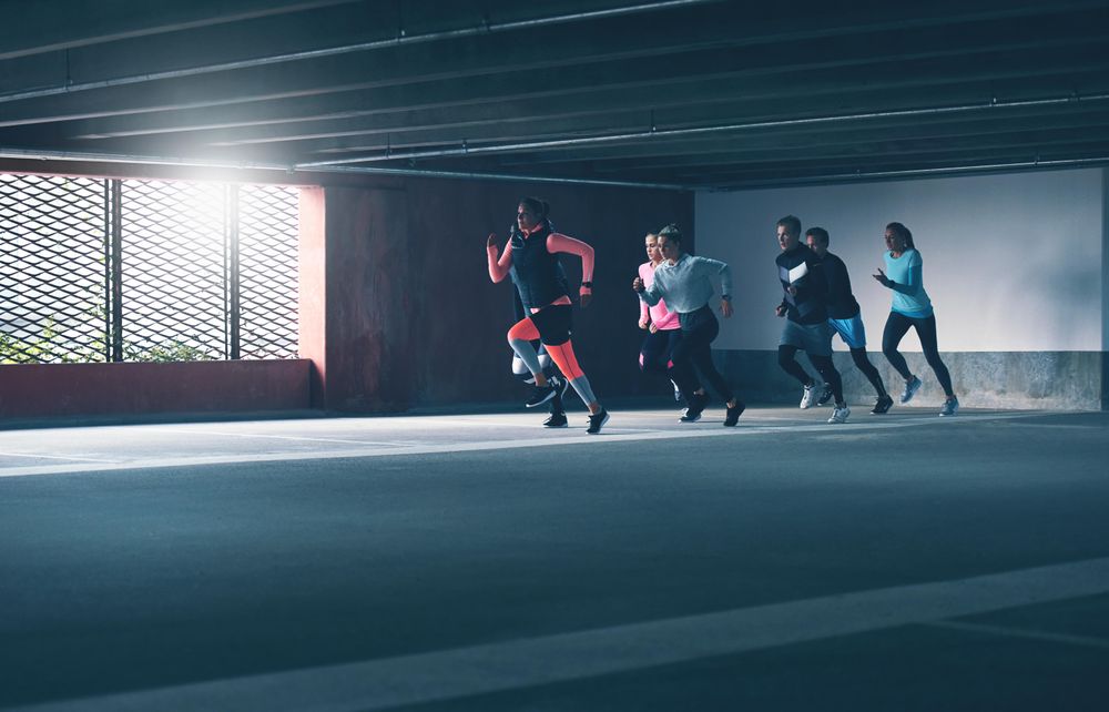 Group of men and women sprinting in concrete space