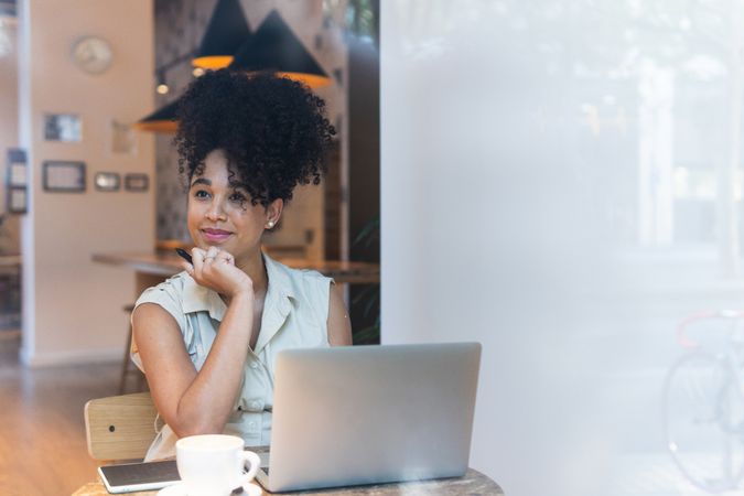 Smiling Black woman working on graphic tablet in cafe