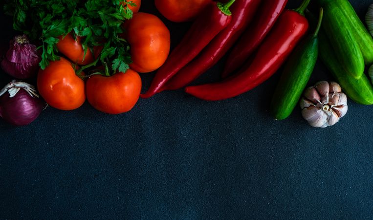 Flat lay of fresh vegetables on dark counter with copy space