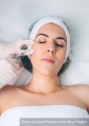 Aesthetician's hand's in latex gloves injecting filler into female's cheek in a beauty salon 4mWE6o