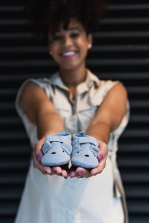Smiling Black woman showing baby booties to camera