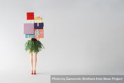 Barbie like doll with skirt made out of green winter branches holding stack of presents 0LPQD0
