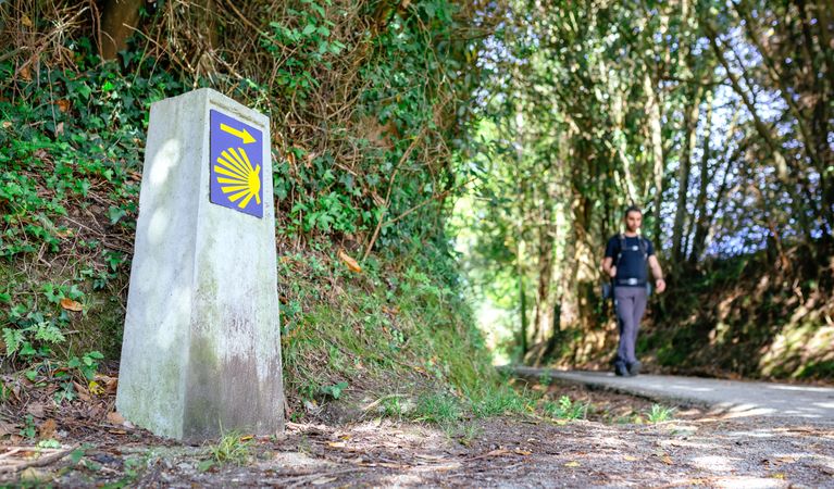 Milestone of Saint James way with pilgrim walking