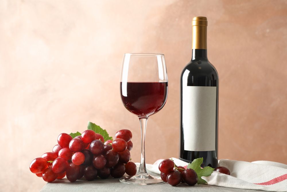 Grape, bottle and glass with wine on grey background, space for text