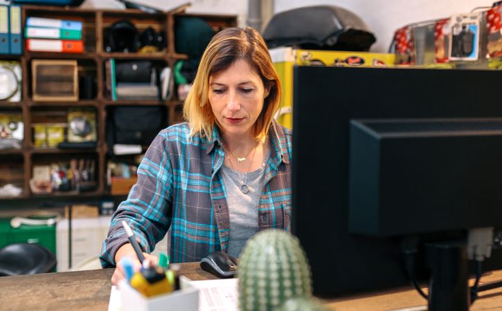 Portrait of blonde young woman filling order forms for ecommerce shop.
