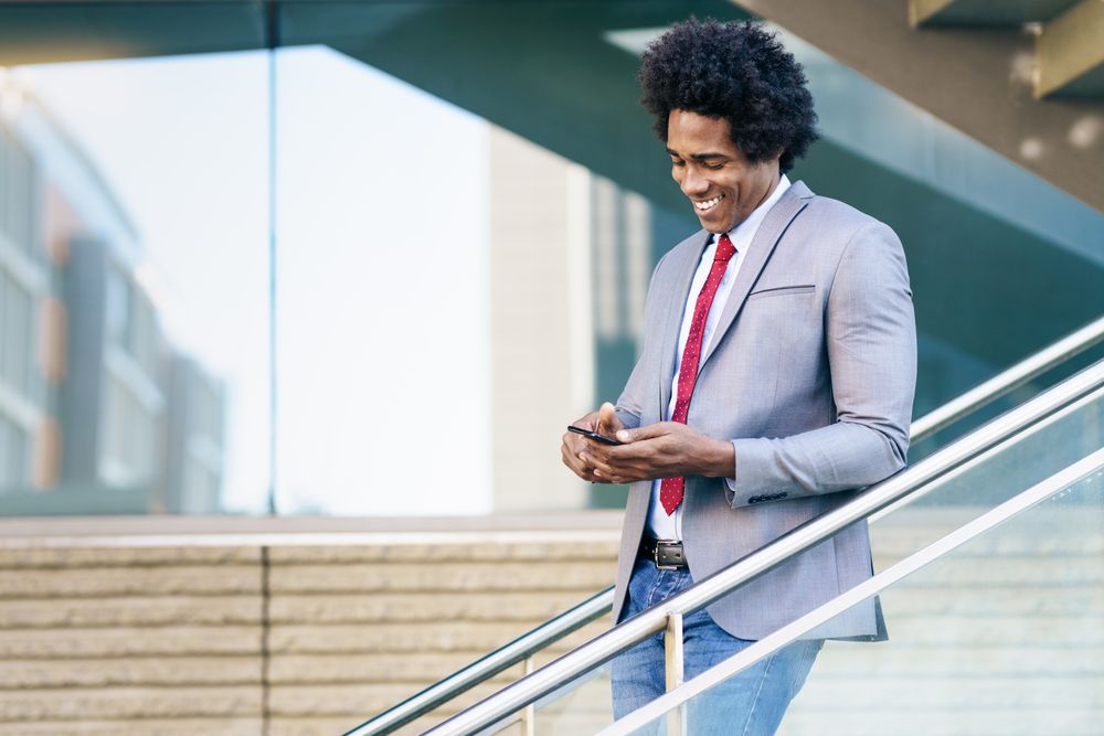 Happy man texting on his phone on staircase