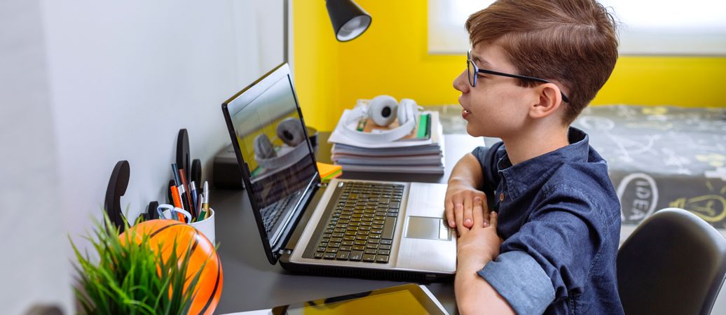 Boy receiving class at home with laptop from his bedroom