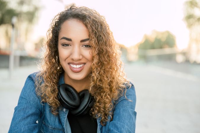Smiling woman with wireless headphones on street