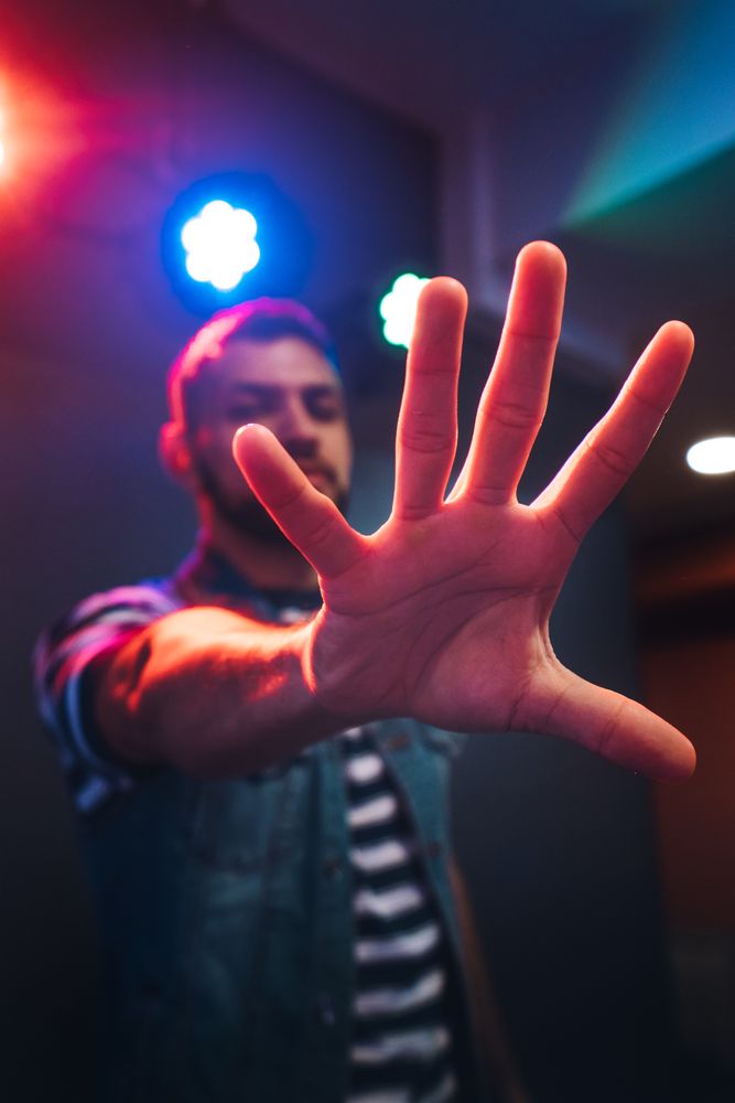 Man dancing in spotlight outstretching hand forward