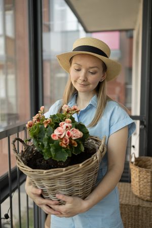 A young woman in a hat holds a plant in her hands