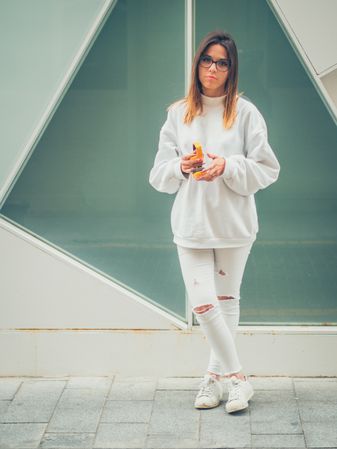 Young woman with headphones standing against wall