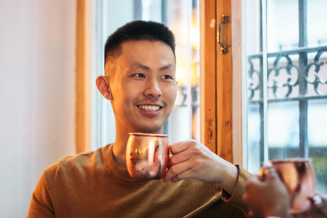 Asian man having a drink in an indoor space