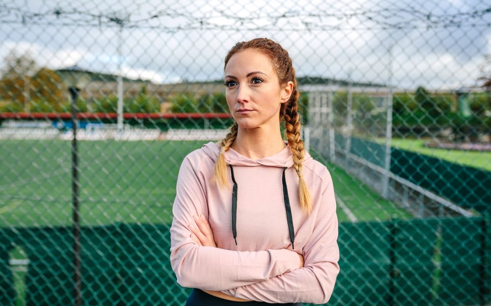 Serious sportswoman with boxer braids posing with crossed arms
