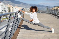 Woman doing splits on bridge railing