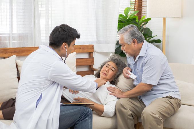 Doctor using stethoscope for older Asian female patient