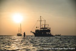 Silhouette of man near sail boat and a ship during sunset 5od8m4