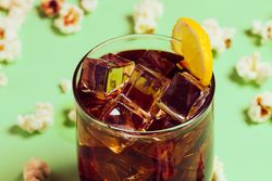 Popcorn on table near drink in glass with ice and lemon