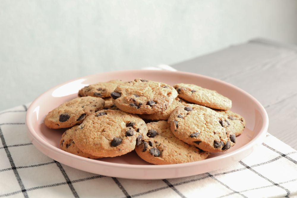 Plate with chocolate chip cookies and space for text on wooden table