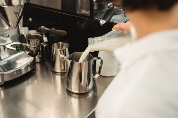 Barista pouring milk to metal pot