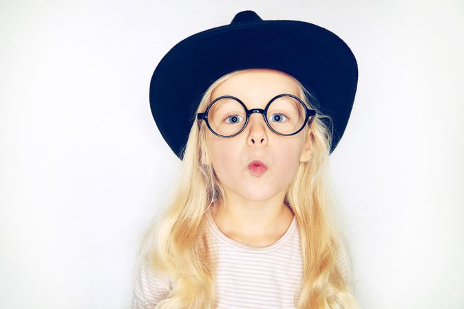 Surprised blonde girl wearing hat and glasses