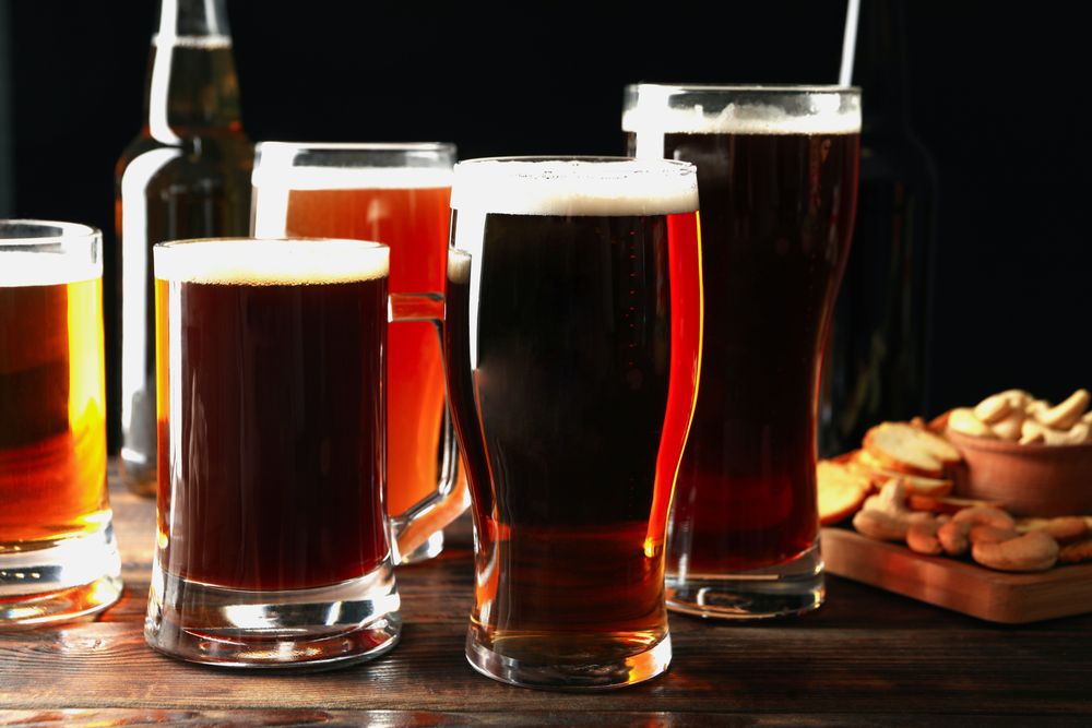 Glasses of beer and snacks on wooden table